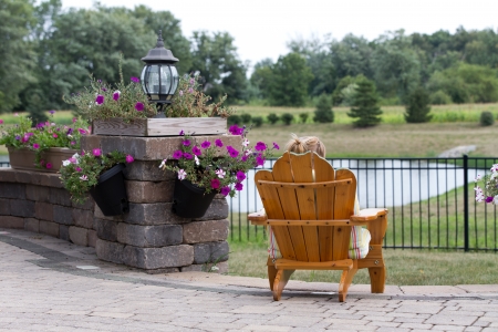 Person relaxing in a garden chair with their back to the camera overlooking open countryside and a small lakeの写真素材