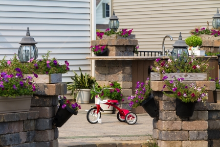 View through an entrance of a kids red tricycle parked in the sunshine in a courtyard amongst pretty potted plantsの写真素材