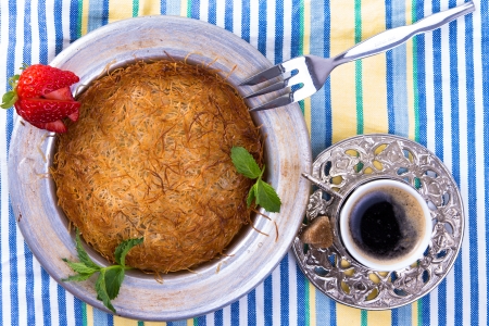 Turkish dessert kunefe isolated on a picnic cloth with mints and sliced strawberry along with Turkish coffeeの写真素材