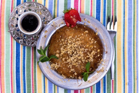 Turkish dessert kunefe on a picnic cloth with mint leaves and sliced strawberry along with Turkish coffee and forkの写真素材