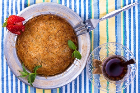 Turkish dessert kunefe isolated on a picnic cloth with mints and sliced strawberry along with Turkish hot teaの写真素材