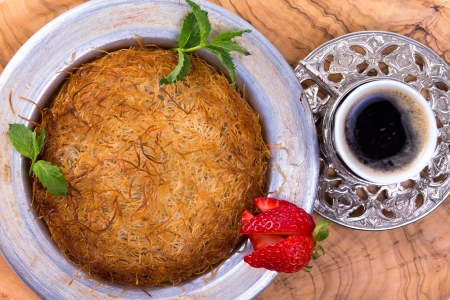 Turkish dessert kunefe isolated on a olive tree table with mints and sliced strawberry along with Turkish coffeeの写真素材