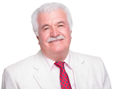 Senior white hair man with a red tie and beige suite smiling satisfiedの写真素材