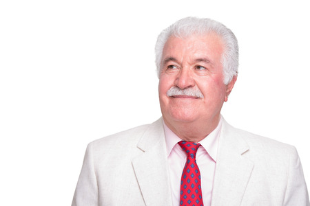 Senior white hair genleman man with a red tie and beige suite looking his right upper side trustfullyの写真素材