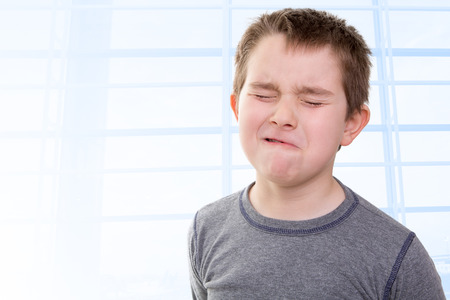 Eight years old kid feeling the pain that shows with his facial expressionの写真素材