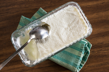 Homemade yogurt ready to serve on a green striped cloth on the table with a spoon in itの写真素材
