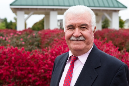 White hair Senior Businessman outside by the red burning bushesの写真素材