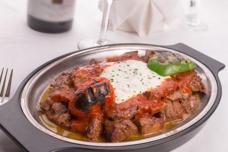 Traditional Turkish Bursa iskender kebap doner served with special red sauce and yogurt in the middle, garnished with grilled tomatoes and peppersの写真素材