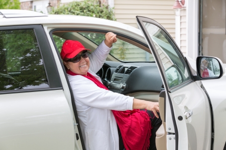 Senior lady with red hat sitting on the passenger seat getting ready close the door and hit the...