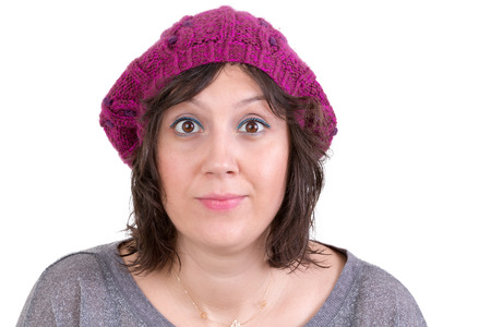Attractive woman wearing a purple knitted winter cap opening her eyes wide in astonishment and scepticism to show her disbelief, isolated on whiteの写真素材