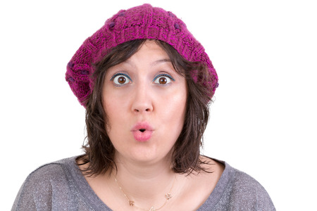Woman wearing a purple knitted beanie reacting in amazement and wonder puckering her lips into an ooh expression with wide eyes, on whiteの写真素材