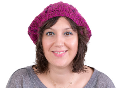 Attractive woman wearing a knitted purple winter hat looking at the camera with a bright friendly smile, isolated on whiteの写真素材
