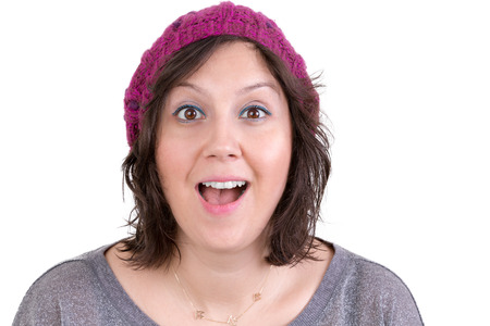 Attractive woman in a knitted cap reacting in delight and pleasure with sparkling eyes and her mouth open wide, isolated on whiteの写真素材