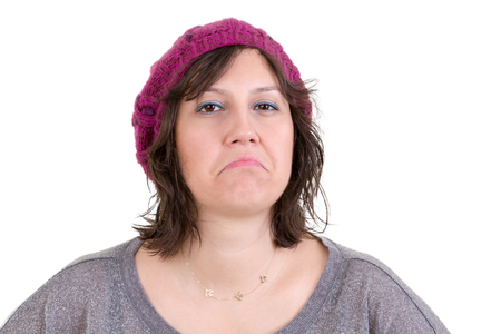 Supercilious disdainful woman in a knitted purple beanie sneering at the camera with a scornful look, head and shoulders on whiteの写真素材