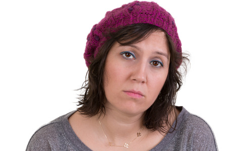 Woman wearing a purple beanie looking at the camera with a mournful woebegone expression and dull eyes, isolated on whiteの写真素材