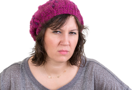 Woman frowning in disbelief with an assessing look peering at the camera with a calculating expression as she tries to fathom the truth, isolated on whiteの写真素材