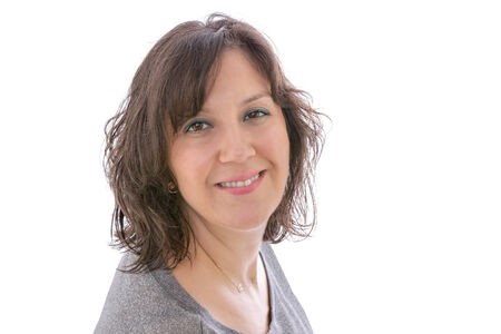 Studio head and shoulders portrait over white, of a smiling brunette woman looking directly to the camera.の写真素材