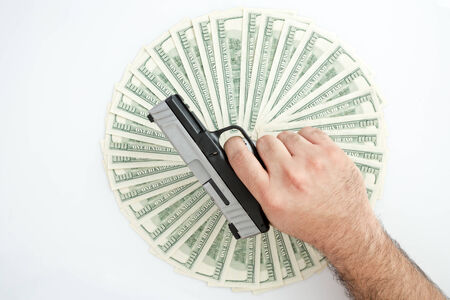Man holding handgun over a stack of moneyの写真素材