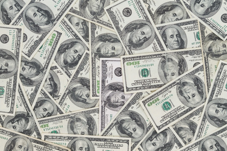 Hundreds of new Benjamin Franklin 100 dollar bills arranged randomly with the portrait facing uppermost in a closeup conceptual financial and monetary backgroundの写真素材
