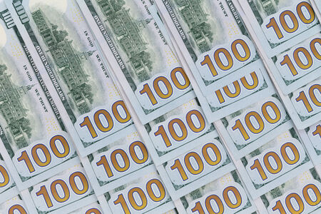 100 dollar American banknotes neatly arranged face down with the denomination numbers aligned in a diagonal pattern in a conceptual financial and monetary backgroundの写真素材