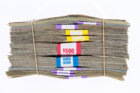 Bank bundles of different denomination dollar bills stacked on top of each other and secured with two rubber bands, side view isolated on whiteの写真素材