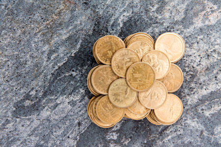 Overhead conceptual financial background image of a pile of neatly stacked dollar coins arranged in a symmetrical pattern on a stone surface with copyspaceの写真素材