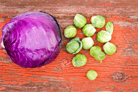 Overhead view of healthy fresh cleaned purple radicchio and brussels sprouts, both cruciferous plants of the Brassica family, on a rustic grunge wooden boardの写真素材