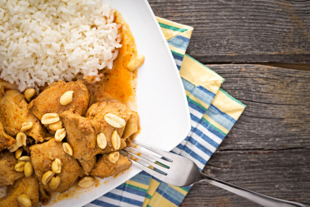 Traditional homemade Thay food made of chicken meat, rice, curry, spicy aromatic sauce and roasted peanuts, on a plate, on a rustic wooden tableの写真素材