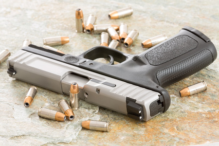 Handgun surrounded with scattered bullets littering the top of an old grungy wooden surface
