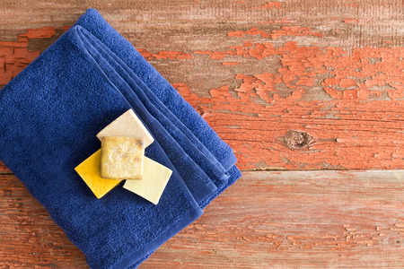 Healthy organic soaps on a neatly folded soft blue towel on rustic wooden boards at a spa or beauty salon for a pampering aromatherapy treatmentの写真素材
