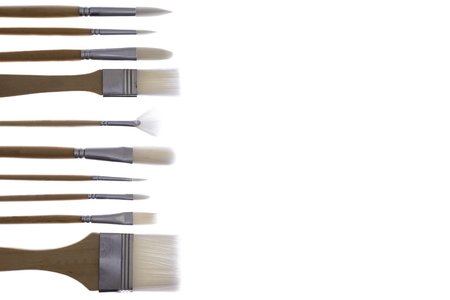 Set of paintbrushes with high key illumination arranged in a neat row as a left border on a white background with copypsace for your text or advertisementの写真素材