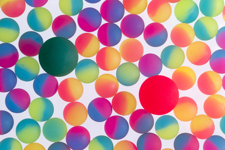 Colorful background of illuminated bicolor plastic balls in the colors of the rainbow arranged in a single full frame layer on a white backgroundの写真素材