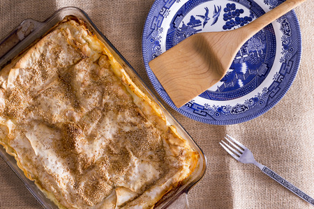 Freshly baked borek or burek, a Balkan pastry made of light flaky phyllo pastry, in an oven dish waiting to be served with a wooden spatula, overhead viewの写真素材