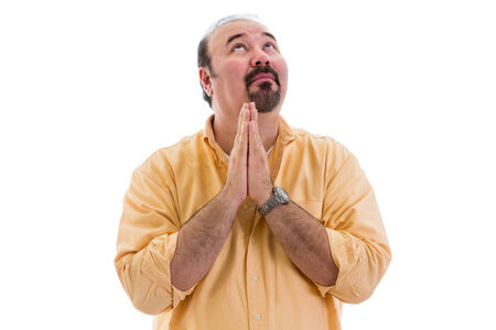 Middle-aged man praying for inspiration and a solution to his problems clasping his hands in prayer and looking to Heaven, part of a series on body language, isolated on whiteの写真素材