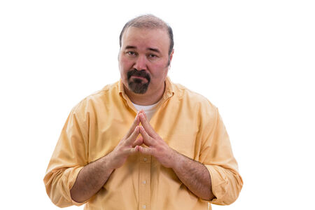 Stern man steepling his fingers as he looks at the camera with a serious expression unmoved by any plea to change his mind on an issue, isolated on whiteの写真素材