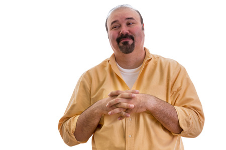 Happy overweight middle-aged man with a goatee clasping his hands over his chest and glancing sideways with a complacent expression and pleased smile, on whiteの写真素材