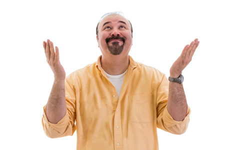 Happy middle-aged man standing celebrating a success or solution raising his hands to heaven in thanks and praise with a beaming smile, on whiteの写真素材