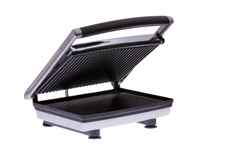 Domestic generic electric panini maker, angled view with the hinged lid partially open to reveal the cast iron plates inside, isolated on whiteの写真素材