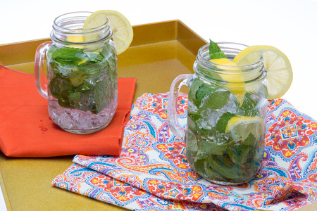 Refreshing chilled drinks lemon and mint in ived water served in glass jars garnised with lemonの写真素材