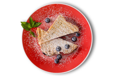 Delicious blueberry jam panini with fresh whole blueberries sprinkled with powdered sugar and garnished with mint served on a colorful orange plateの写真素材