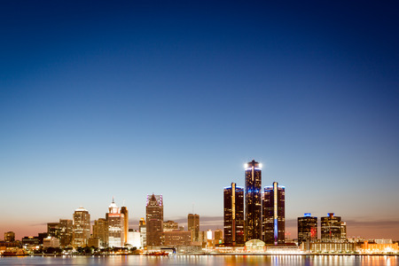 Detroit, Michigan skyline at twilight with the illuminated lights of the waterfront buildings in the CBD reflected in the water of the Detroit Riverの写真素材