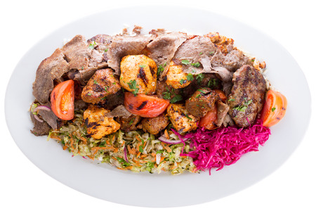 Plate of delicious grilled mixed shish kebabs with beef and chicken served with fresh greens, red cabbage and tomato and lamb kofte isolated on whiteの写真素材