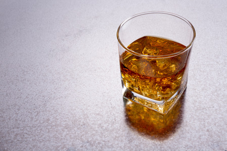 High angle view of a glass of whiskey on a shiny textured metal bar counter with copyspace to the left and a reflectionの写真素材