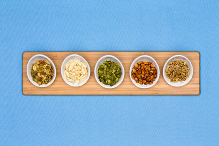 Different types of nuts presented in tater cups on blue backgroundの写真素材