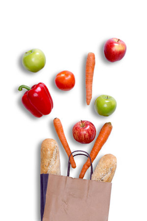 Fresh balanced grocery shopping concept with a brown paper carrier bag with fresh crusty baguette, carrots, apples, sweet bell pepper and tomato arranged on a white surface, view from aboveの写真素材