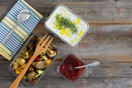 Healthy meal of roasted or grilled assorted vegetables including sweet pepper, eggplant and zucchini served with tzatziki or Turkish cacik with yogurt and dill and a pepper paste on an old wood tableの写真素材