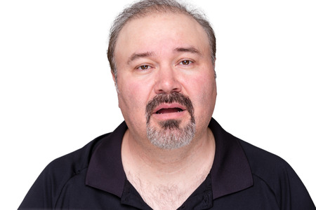 Unmotivated lethargic middle-aged man with a goatee beard looking a the camera with a dim-witted expression and his mouth ajar, isolated on whiteの写真素材