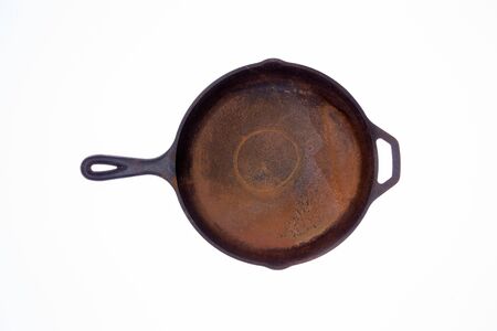 Old rusty round black cast iron frying pan viewed from above isolated on a white background centered in the frameの写真素材