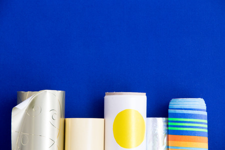 Colorful rolls of decorative patterned gift wrap in a bottom border over a vibrant blue with copyspace for a festive eventの写真素材