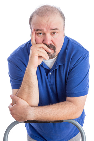 Close up Thoughtful Adult Bearded Man Leaning Against the Back of a Chair with Hand on his Face and Looking at the Camera. Isolated on White.の写真素材